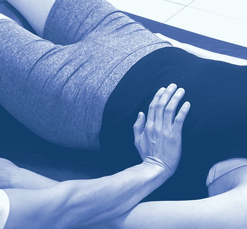 A therapist’s hand resting lightly on the hip of a patient lying on their side on the table